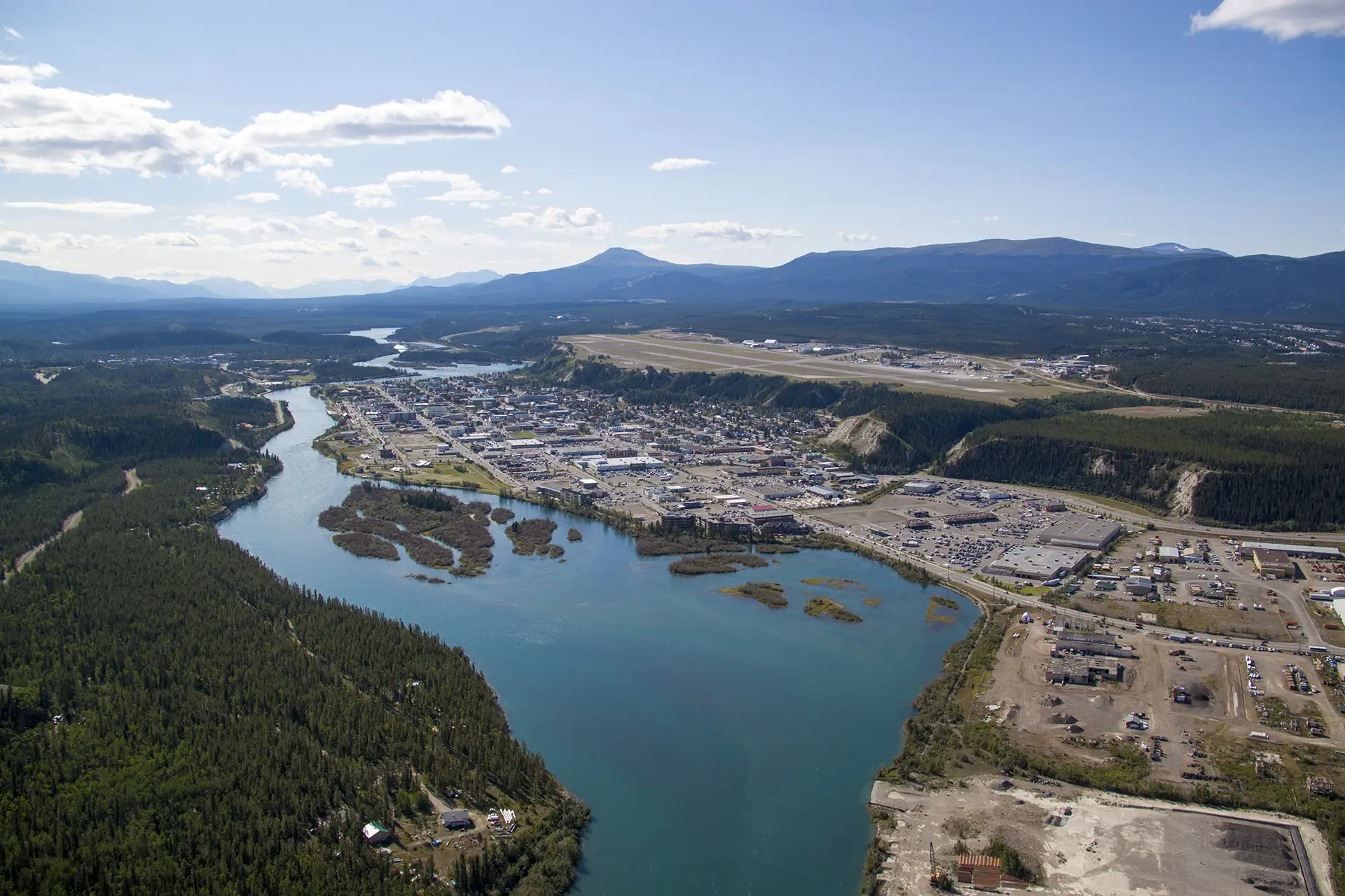 Aerial photo of Whitehorse, from north side showing the Yukon River alongside the town.